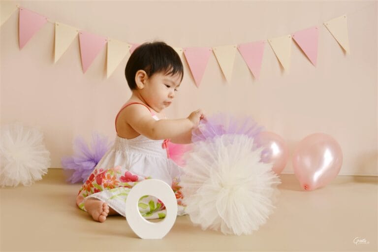 Cute baby making playing with photography prop during a portrait session before a cake smash session in South West London.
