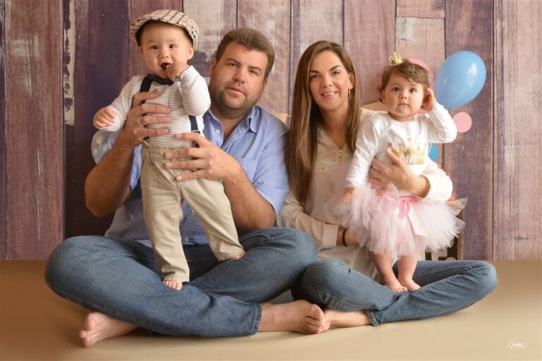 Baby twins posing with parents during cake smash photo session in a Kingston photography studio.